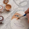 A hand painting a numbered section of the custom artwork, with matching paint nearby