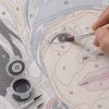 A hand painting a numbered section of the custom artwork, with matching paint nearby