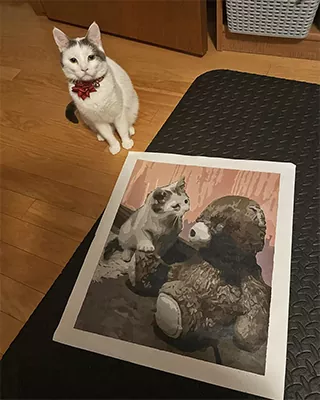 A curious cat and its custom portrait displayed side by side