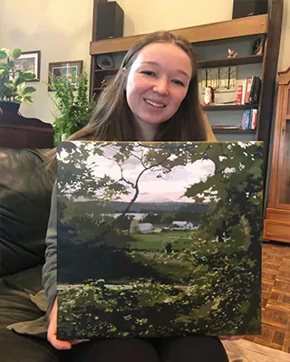 Customer holding a completed custom paint by numbers landscape canvas with a countryside view