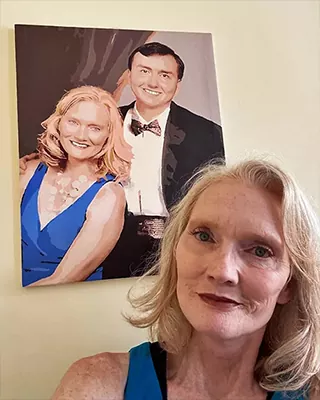 Proud customer posing beside a personalized paint by numbers portrait of a special couple