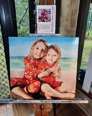 Two sisters sharing a beachside hug in a custom painted keepsake