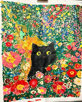 Black cat with bright yellow eyes surrounded by a vibrant wildflower garden
