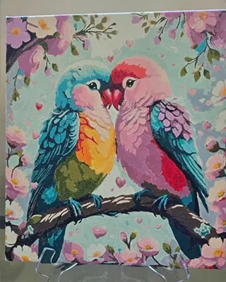 Colorful lovebirds perched together among soft pink blossoms and tiny hearts