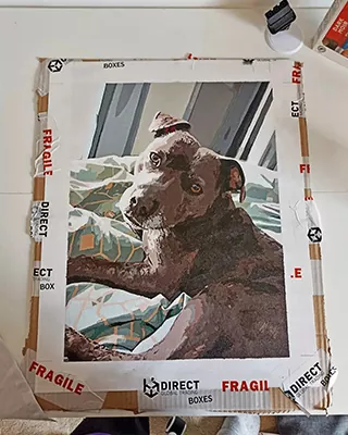 Custom paint by numbers portrait of a dark-coated dog relaxing on a bed