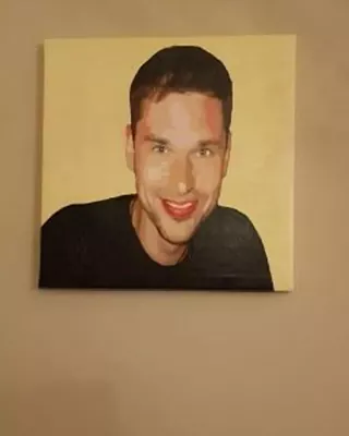 Custom paint by numbers portrait of a smiling man displayed on a wall