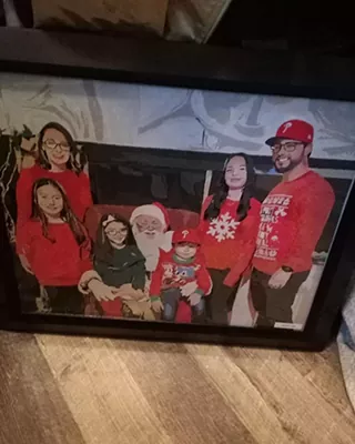 Framed custom paint by numbers artwork of a family posing with Santa at Christmas