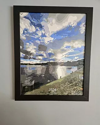 Framed custom paint by numbers landscape of a calm lake beneath a dramatic blue and cloudy sky