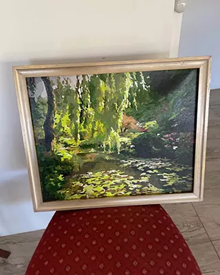 Framed paint by numbers artwork of a peaceful garden pond surrounded by lush green trees