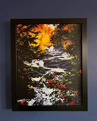 Framed woodland stream painting glowing with rich fall colors