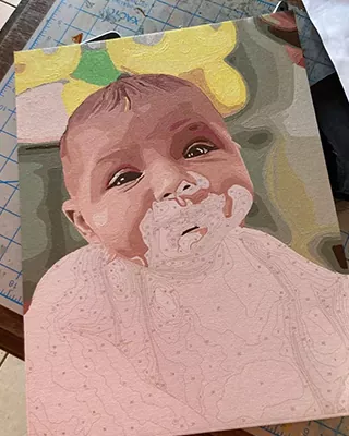 In progress custom baby portrait with a smiling infant covered in cake frosting