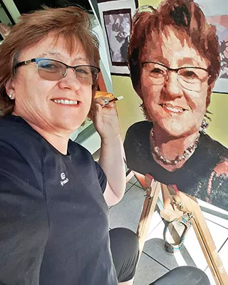 Side by side view of a woman and her finished custom paint by numbers portrait.