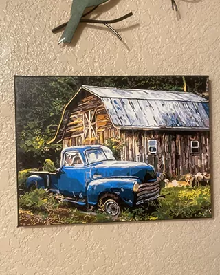 Vintage blue pickup truck beside a rustic wooden barn