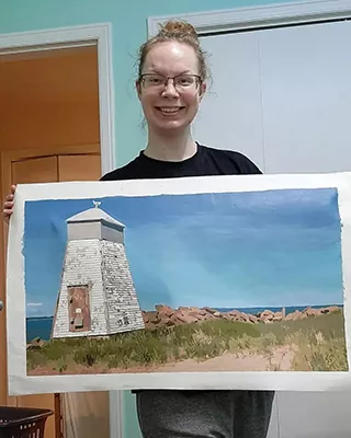 Woman holding a custom paint by numbers artwork of a coastal lighthouse
