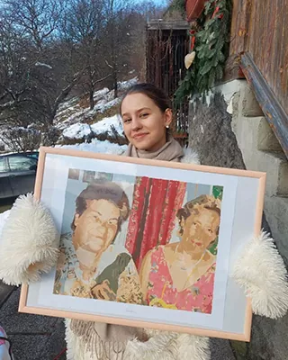 Woman holding a framed custom paint by numbers portrait of two people