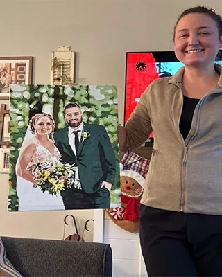 Woman proudly holding a custom paint by numbers wedding portrait of a bride and groom